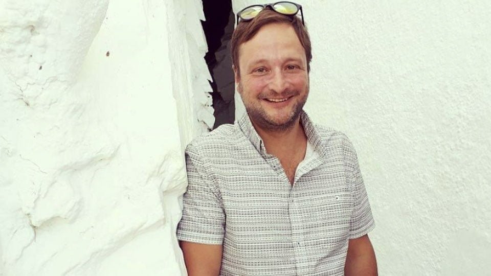 Fabricio Azevado leaning against a wall whilst smiling at the camera